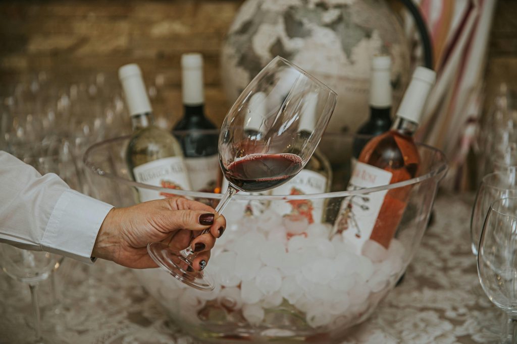 Hand holding a wine glass above a bowl with bottles, perfect for wine tasting themes.