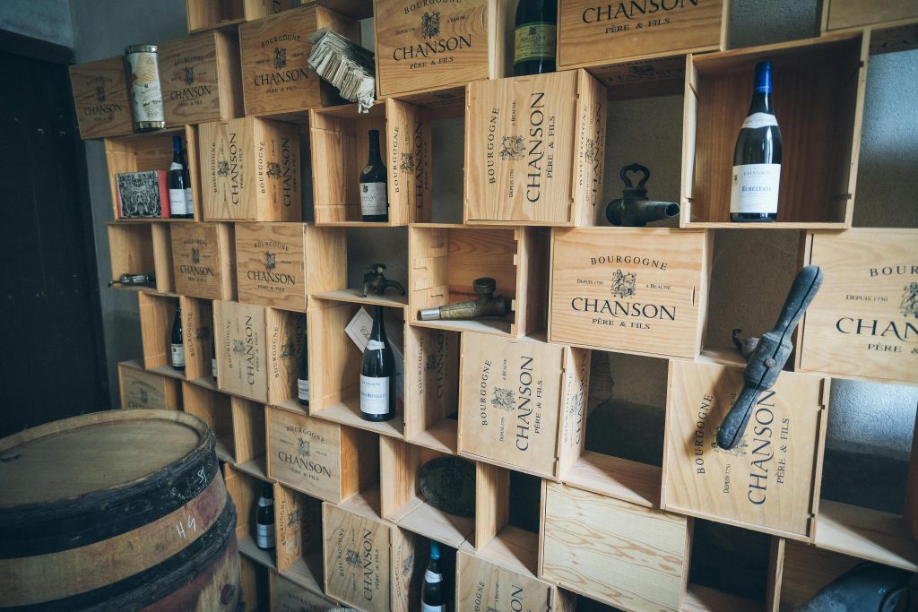Explained: The Truth About Wine Bottle Shock Rustic wine cellar featuring wooden shelves filled with Chanson wine crates and vintage bottles.