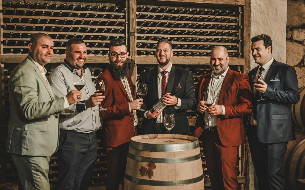 6 Wine Tasting Mistakes You're Probably Making Six men in suits enjoying red wine in an upscale wine cellar setting.