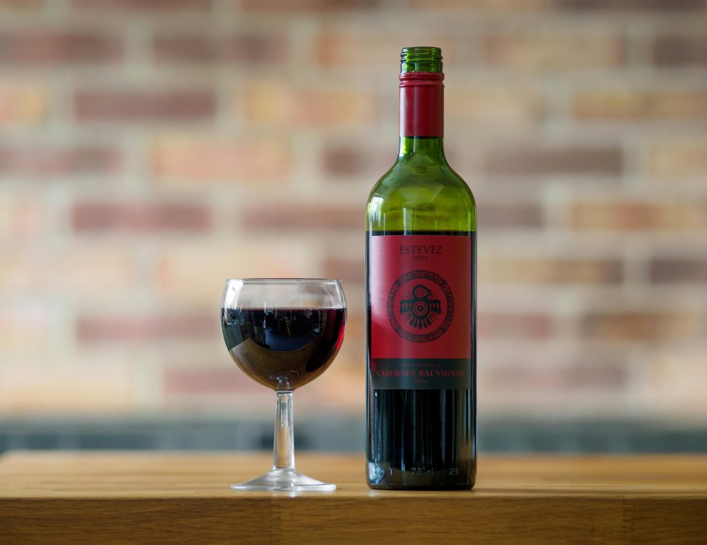 Elegant presentation of a Cabernet Sauvignon bottle and glass on a wooden table.