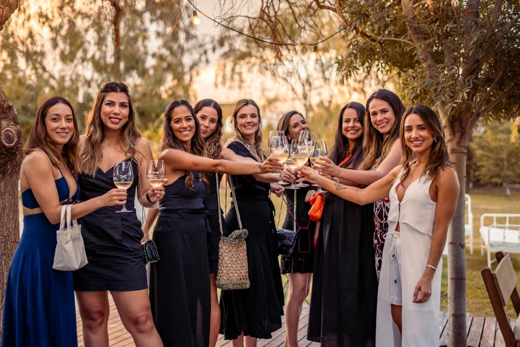 Is Wine Vegan? What Every Wine Drinker Should Know A group of women enjoying a celebratory toast outdoors at sunset in stylish dresses.