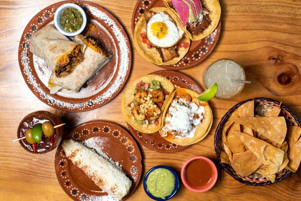 Delicious Mexican dishes including tacos and burritos served on rustic plates with refreshing drinks.