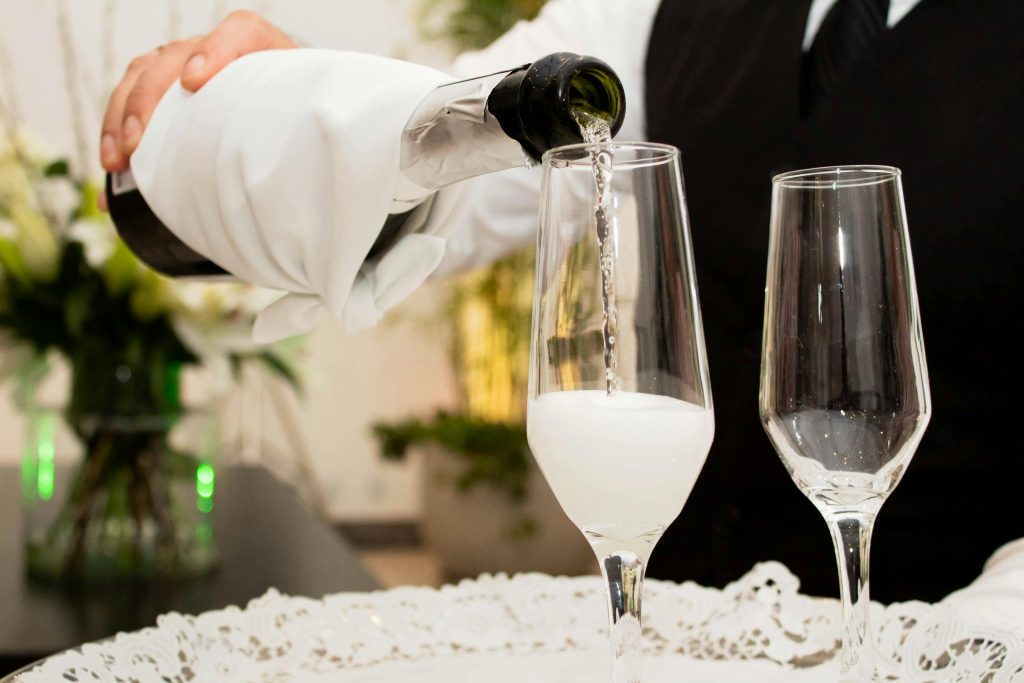 Wine Moments from Iconic Films: Scenes Worth Savoring Close-up of champagne being poured into glasses at a sophisticated celebration.