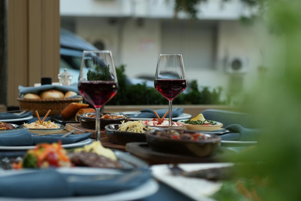 Luxurious outdoor table setting featuring red wine and a variety of gourmet dishes for a sophisticated dining experience.