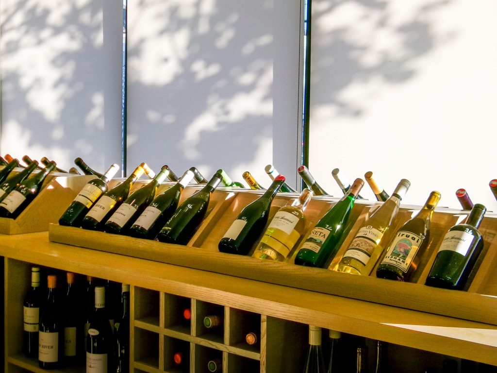 An inviting display of various wine bottles in a modern shop setting, illuminated by natural light.