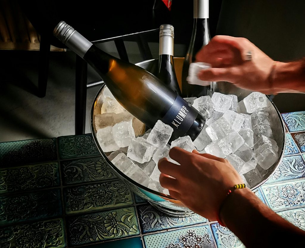 Close-up of wine bottles on ice in a bucket with vibrant tile background, creating a sophisticated atmosphere.