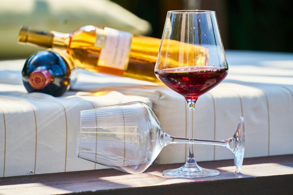 Close-up of wine glasses with bottles, set on a cozy outdoor lounge, capturing a relaxing moment.