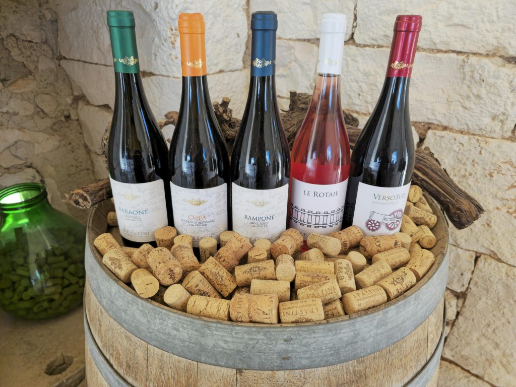 How to Pair Wine With BBQ: 5 Simple Rules A rustic display of diverse wine bottles and corks on a barrel with a stone wall background.
