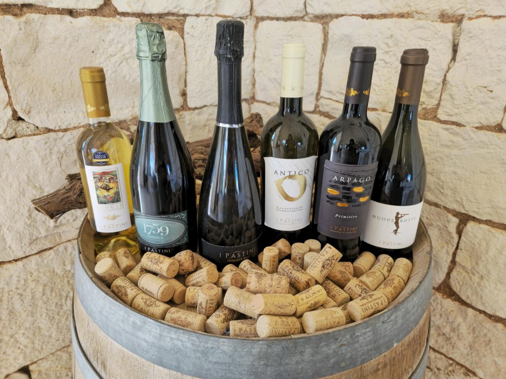 BuyWinesOnline.com Review: Best for Self-Select Shoppers? Five Italian wine bottles displayed on a rustic barrel surrounded by corks.