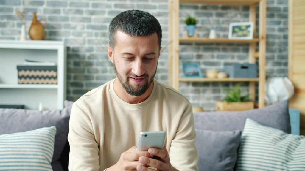 Is Wine Vegan? What Every Wine Drinker Should Know Casually dressed man using smartphone while sitting on a cozy sofa in a modern living room.