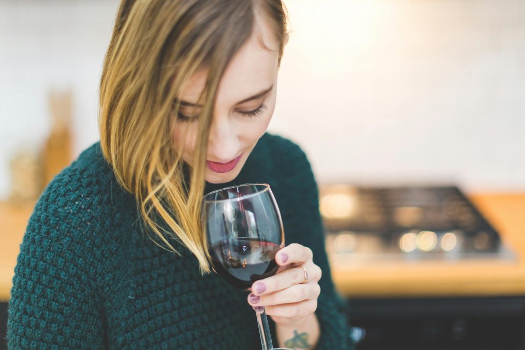 6 Wine Tasting Mistakes You're Probably Making A young woman savoring a glass of red wine in a cozy indoor setting, capturing the essence of relaxation and leisure.