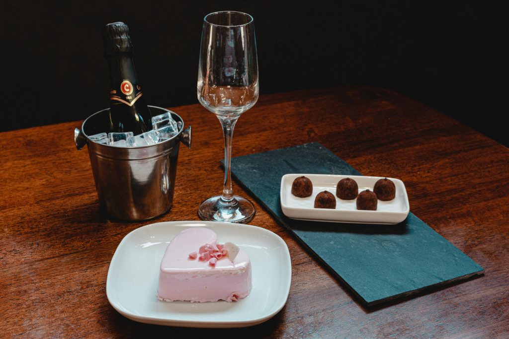 Heart-shaped dessert with champagne on a wooden table, perfect for celebrations and romantic moments.