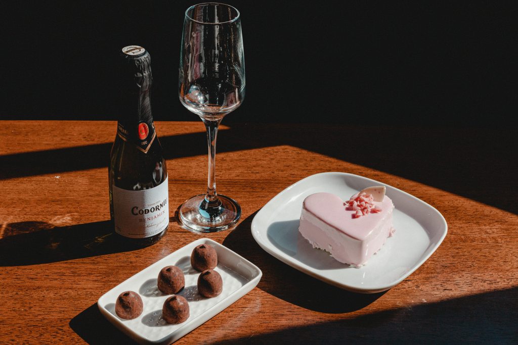 7 Tasty Pairings For Dessert and Wine Heart-shaped cake and chocolates with champagne on a wooden table, ideal for celebrations.