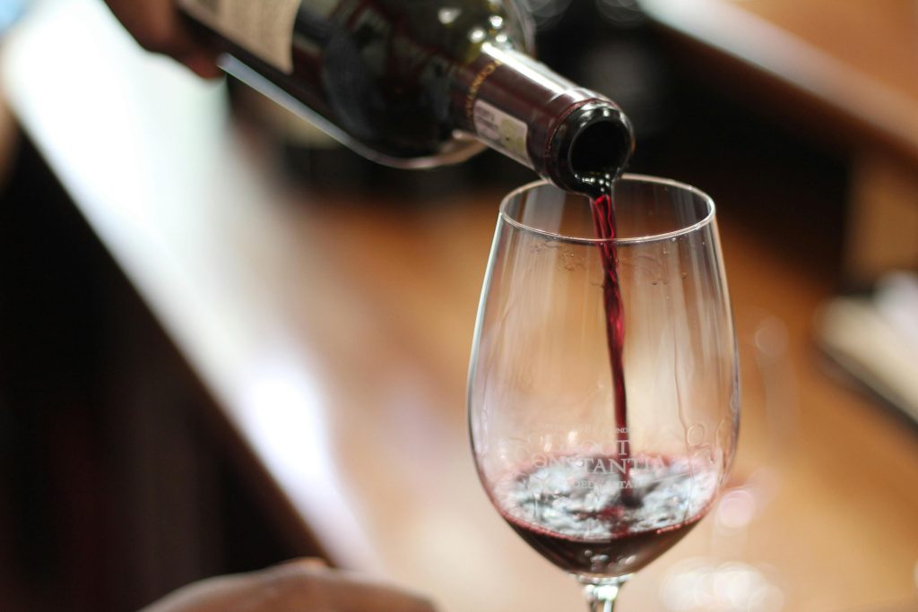 Is Wine Vegan? What Every Wine Drinker Should Know Close-up of red wine being poured into a glass with a selective focus and blurry background.