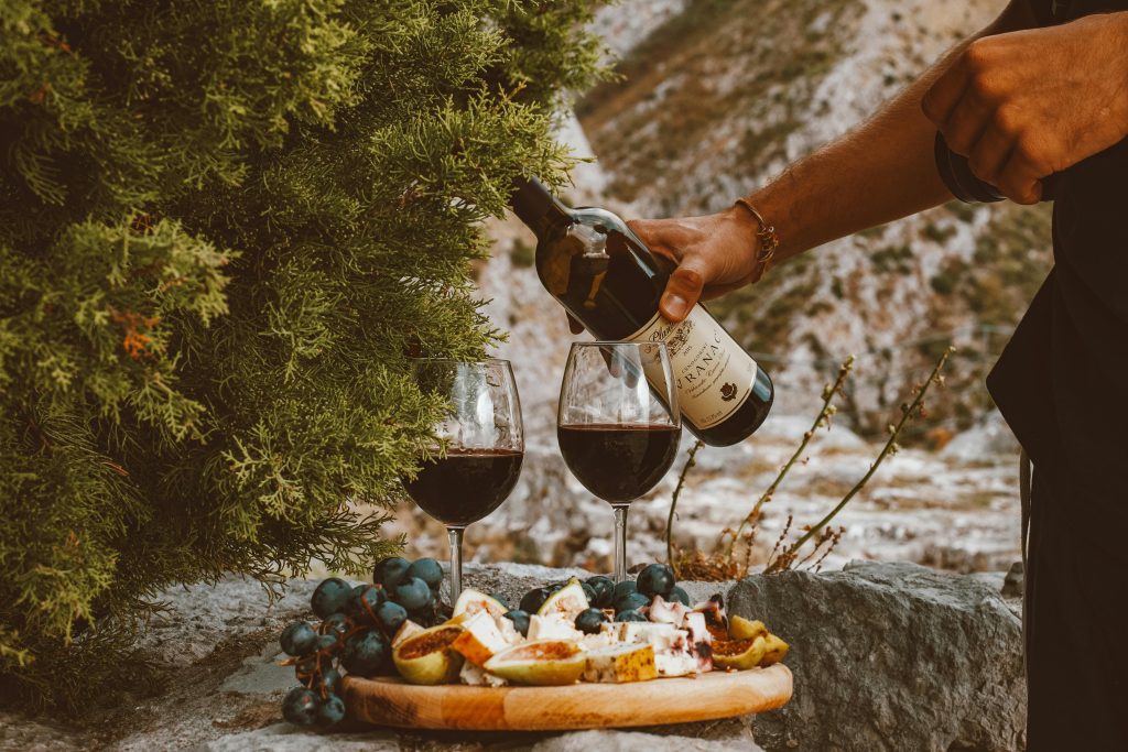 BuyWinesOnline.com Review: Best for Self-Select Shoppers? A scenic outdoor setting with red wine, cheese, and grapes on a stone surface.
