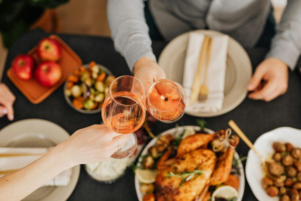 Rosé Wine Guide: Everything You Need to Know A festive holiday dinner scene with people toasting wine glasses over a delicious meal.