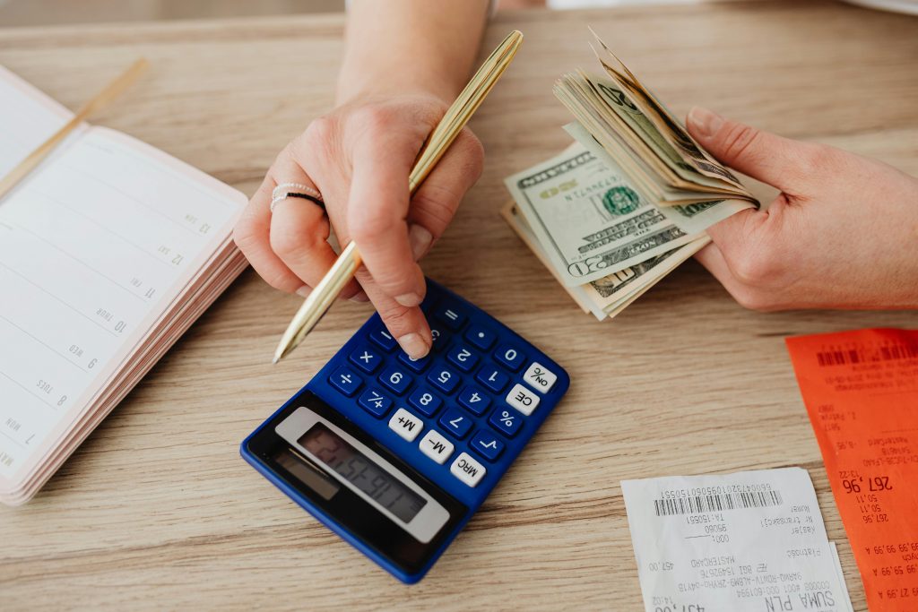 6 Smart Tips for Choosing Wine as a Gift Hands handling cash and calculator for budget planning. Modern financial scene.