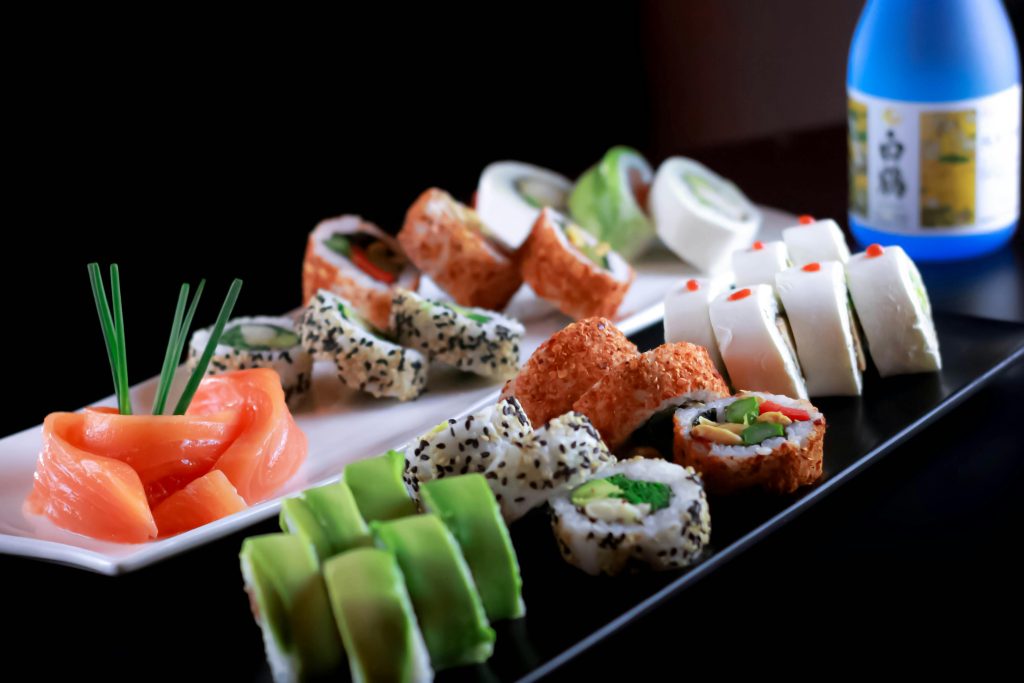 A beautifully arranged sushi platter featuring an assortment of maki, sashimi, and nigiri paired with sake.