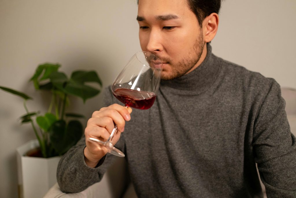 Adult man enjoying red wine indoors, focused on aroma. Cozy, relaxed setting.