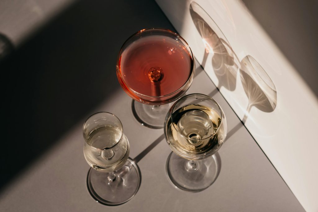 Three different wine glasses casting unique shadows in natural sunlight, showcasing elegance and variety.