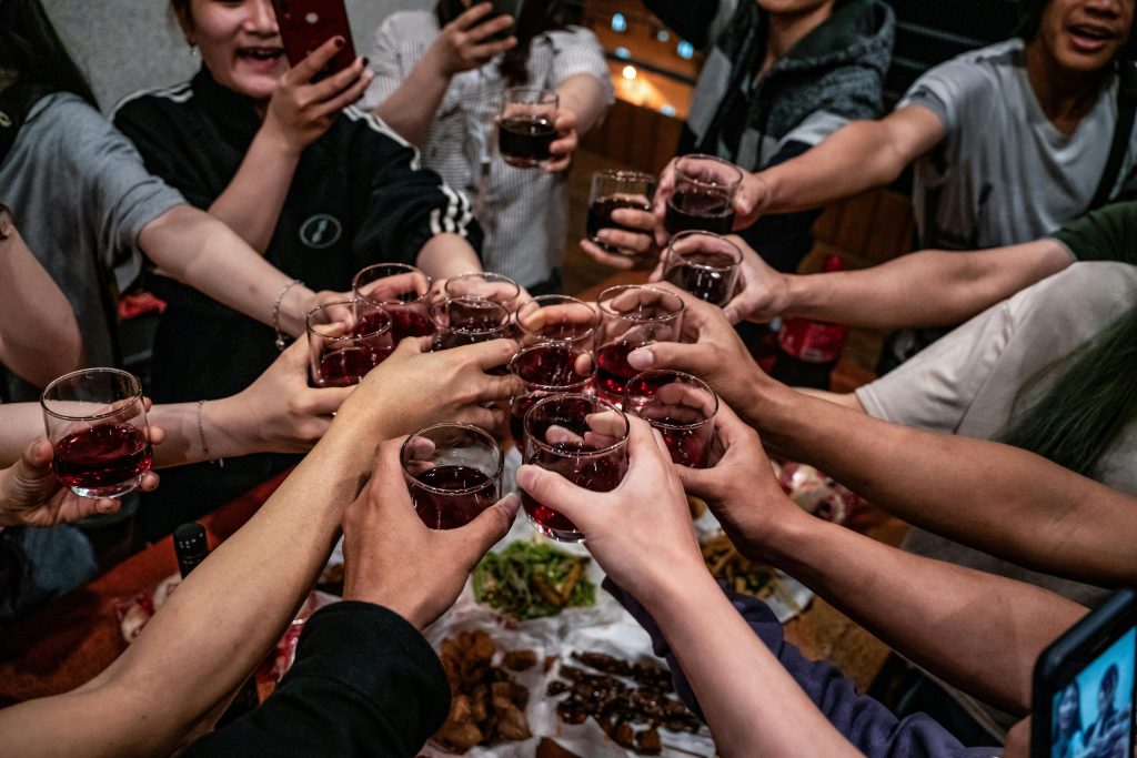 BuyWinesOnline.com Review: Best for Self-Select Shoppers? A diverse group of friends toasting with red wine glasses in a lively indoor setting, celebrating togetherness.