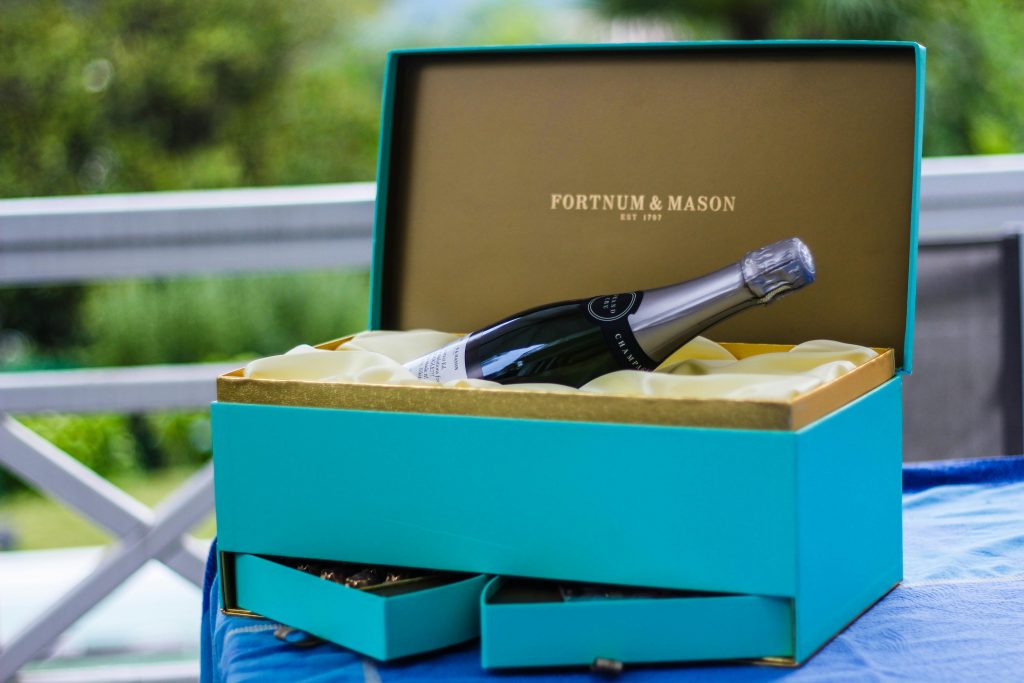 6 Smart Tips for Choosing Wine as a Gift Elegant Fortnum & Mason gift with champagne bottle on table outdoors.