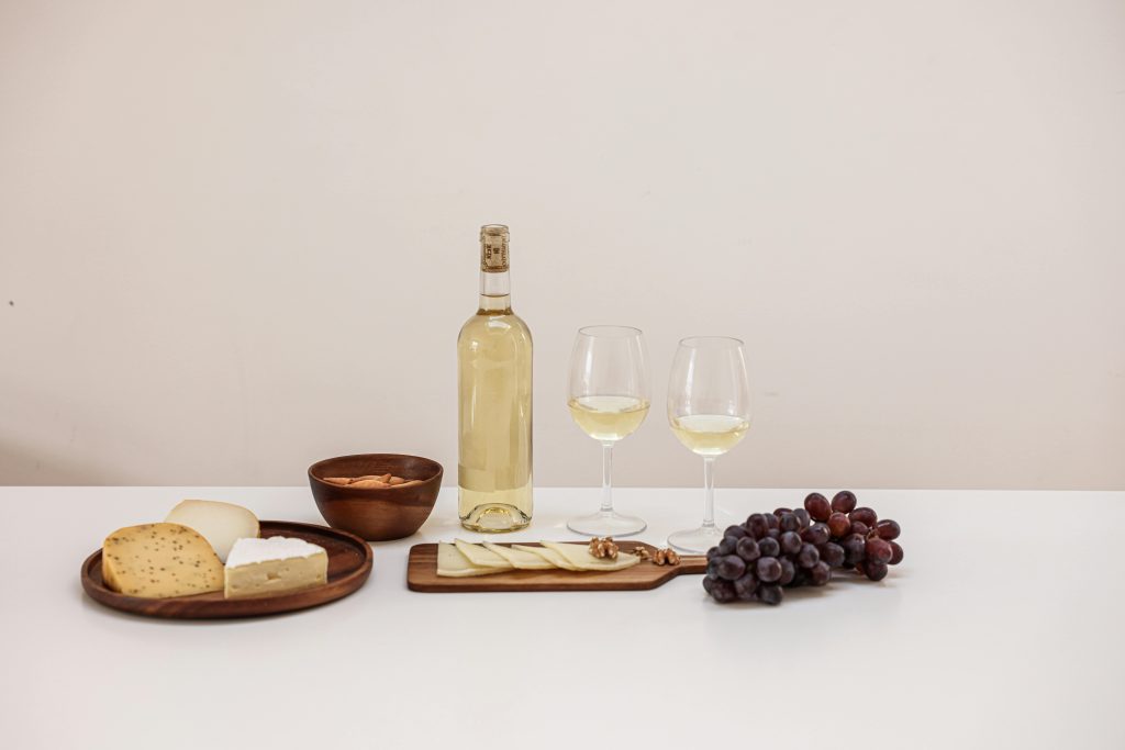 Sweet Wine Guide: Best Types and Bottles to Try A stylish arrangement of cheese, wine, grapes, and nuts on a minimalist table setting.