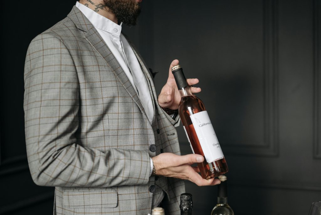 Elegant man in a suit holding a wine bottle, showcasing in a sophisticated setting.