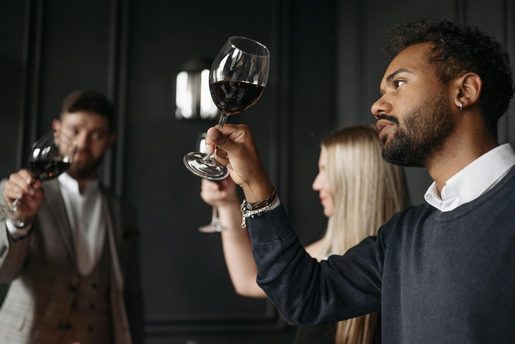 A diverse group tasting wine indoors, focusing on details with glasses raised.