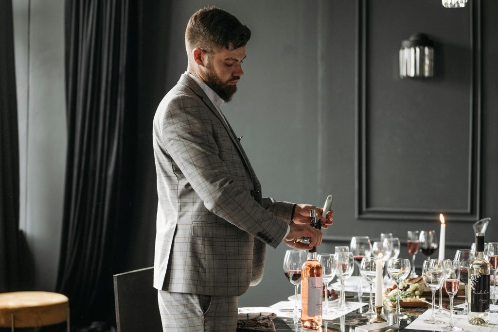 Rosé Wine Guide: Everything You Need to Know A sommelier opening wine bottles for a formal wine tasting setup indoors.