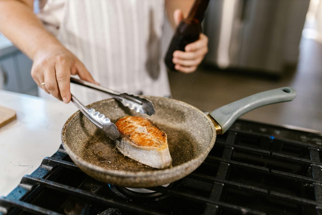 Wine and Salmon Pairing: The Complete Guide A close-up shot of a salmon steak being grilled in a non-stick pan in a kitchen setting. Perfect for cooking enthusiasts.