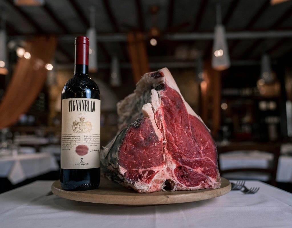 Wine and Steak Pairing: Best Bottles for Every Cut A luxurious pairing of raw steak with a bottle of premium red wine on a restaurant table.