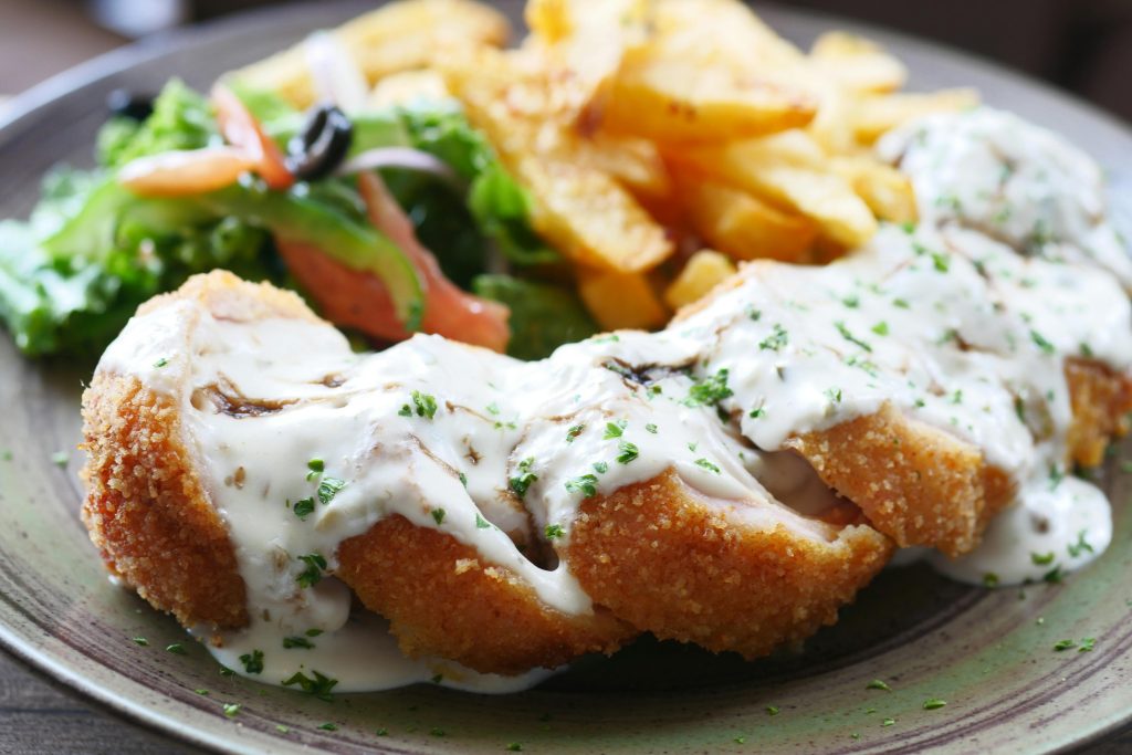 Crispy breaded chicken with sauce, served with fries and fresh salad.