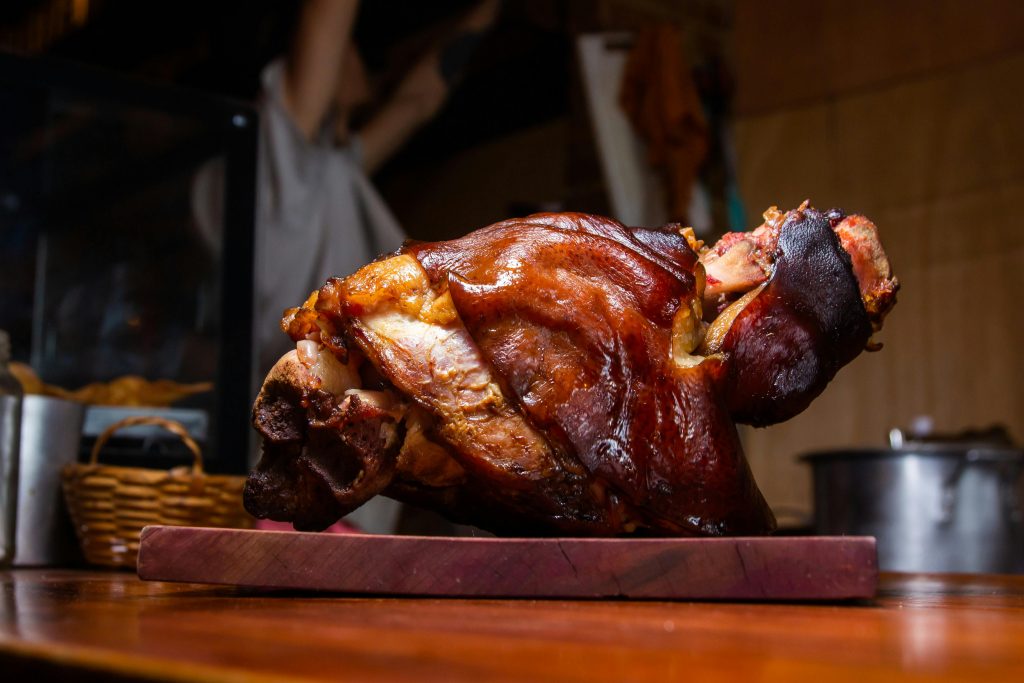 Close-up of a crispy roasted pork knuckle on a wooden cutting board, perfect for stock imagery.
