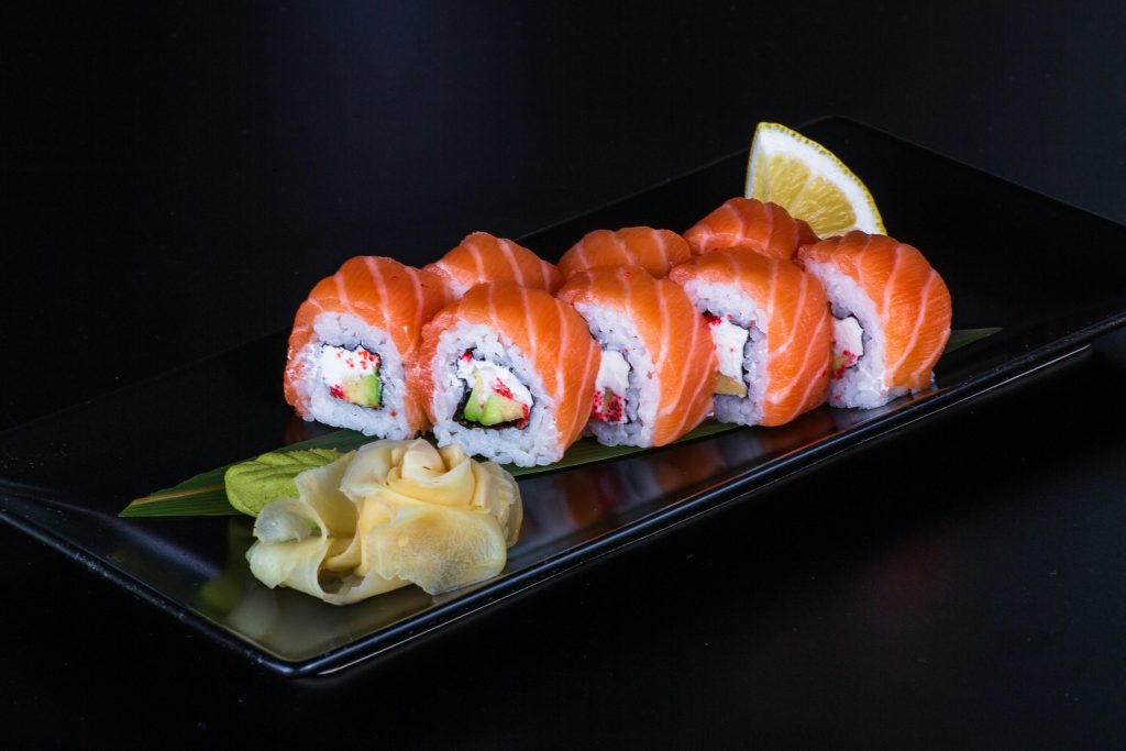 Wine and Salmon Pairing: The Complete Guide Close-up of salmon sushi rolls with ginger on a black plate, perfect for food photography.