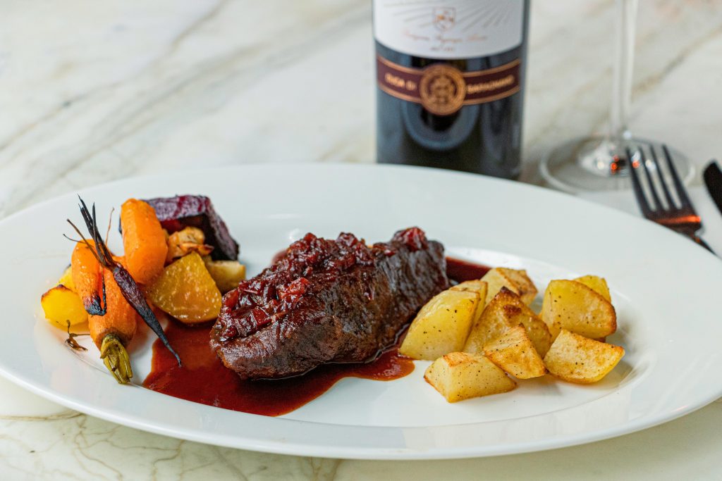 Delicious gourmet beef served with roasted vegetables and red wine.