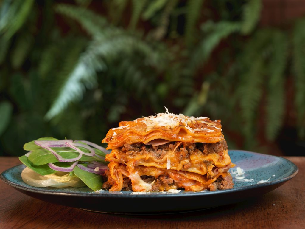 Appetizing lasagna served with a fresh salad, highlighted by vibrant colors and textures.