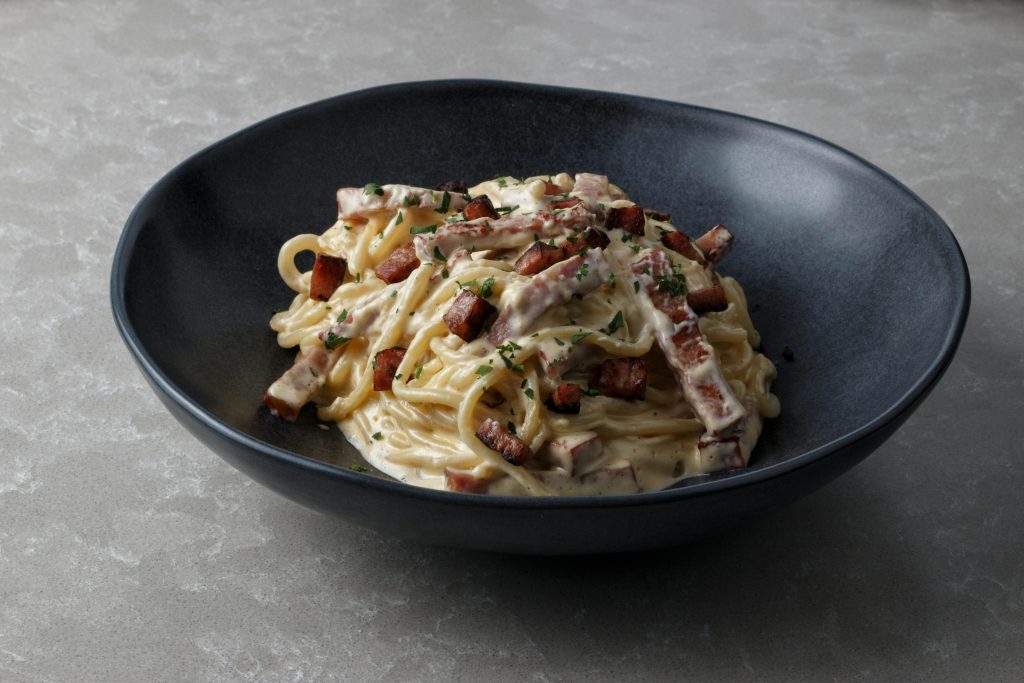 Mouth-watering spaghetti carbonara with creamy sauce and crispy bacon bits served in a bowl.