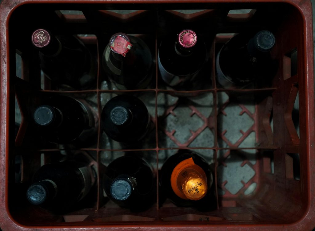 Overhead shot of assorted wine bottles in a red plastic crate showcasing storage arrangement.