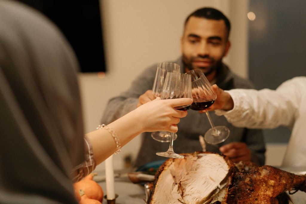 Adults toasting with red wine at a festive Thanksgiving dinner indoors.