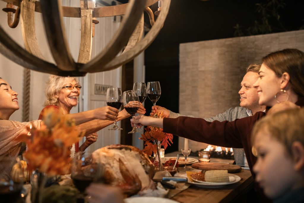 A joyful family toasting with wine glasses at a festive Thanksgiving dinner indoors.
