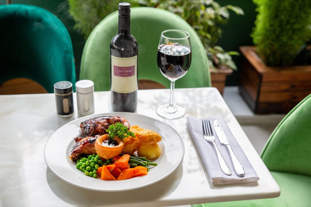 A delicious roast beef meal with vegetables, paired with red wine, elegantly set on a table.