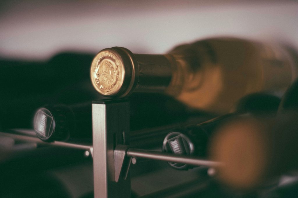 Soft focus of glass bottles with alcohol drinks placed on metal shelves in modern winery cellar with collection of alcohol on blurred background
