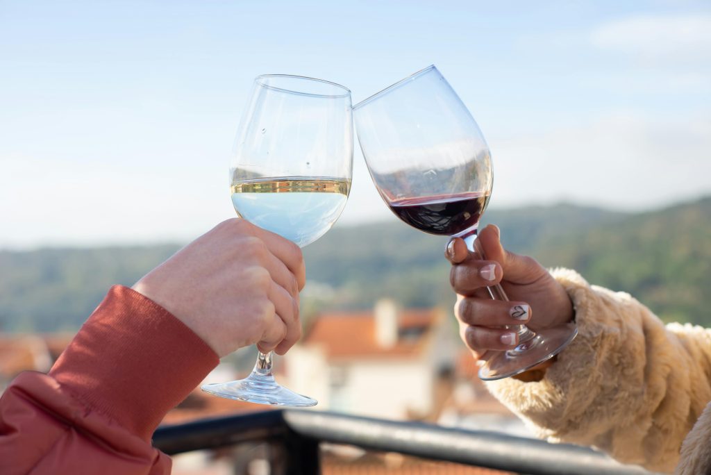 Two people clinking wine glasses on a sunny day in Portugal, capturing a moment of celebration.