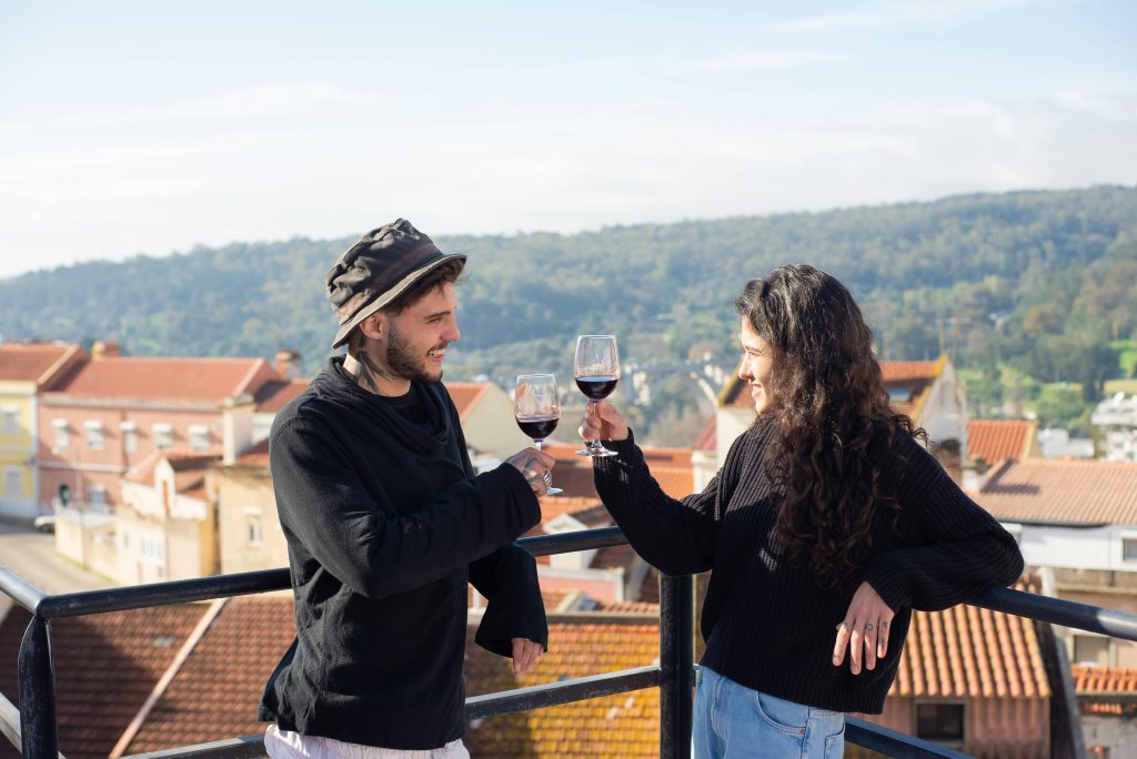 Two friends enjoying wine and celebrating on a picturesque rooftop in Italy.