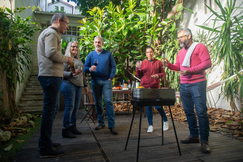 Best Wines for a Summer BBQ A lively gathering of adults enjoying a barbecue and drinks in a Portuguese garden.