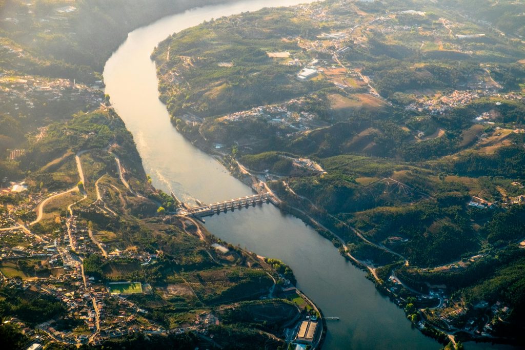A stunning aerial image of Crestuma Dam on the Douro River in Portugal, capturing lush landscapes from above.