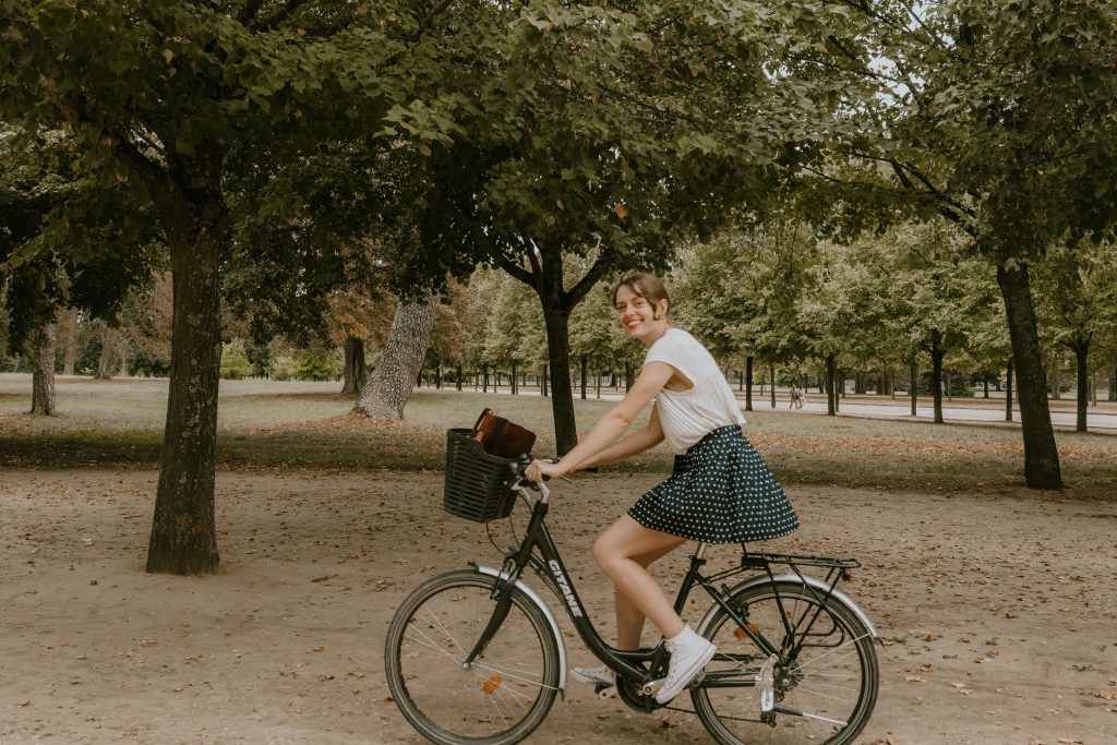Young woman riding a bicycle in a beautiful Paris park during the day.