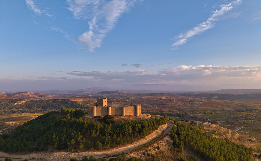 Stunning aerial view of Clavijo Castle surrounded by scenic La Rioja landscape at sunset.