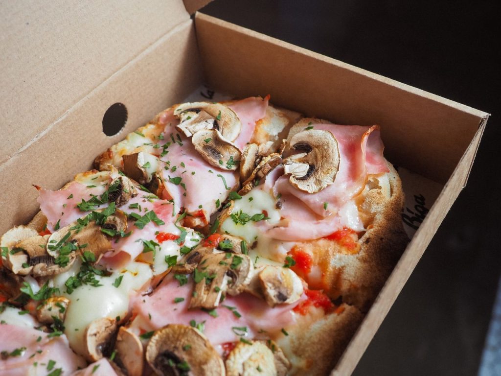 Delicious mushroom and ham pizza in a takeaway box, perfect for a quick meal.